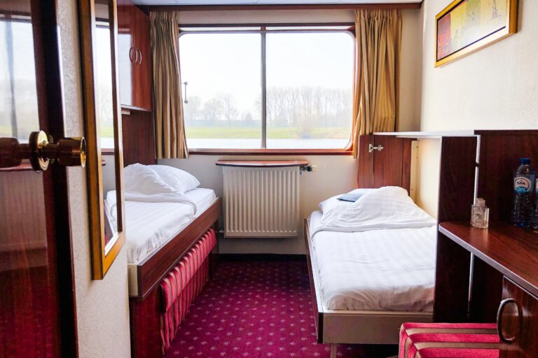 Twin cabin with single beds and panoramic window on a European river cruise ship.