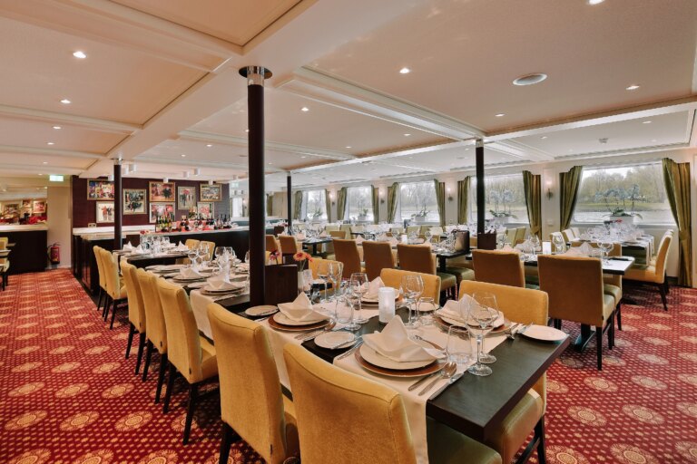 Spacious dining room with panoramic windows and decorated tables on a European river cruise ship.