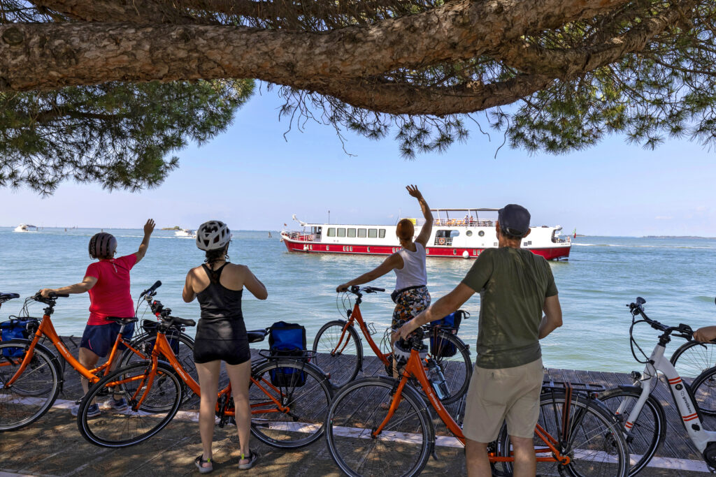 Group of cyclists salute "Ave Maria" while sailing in the lagoon