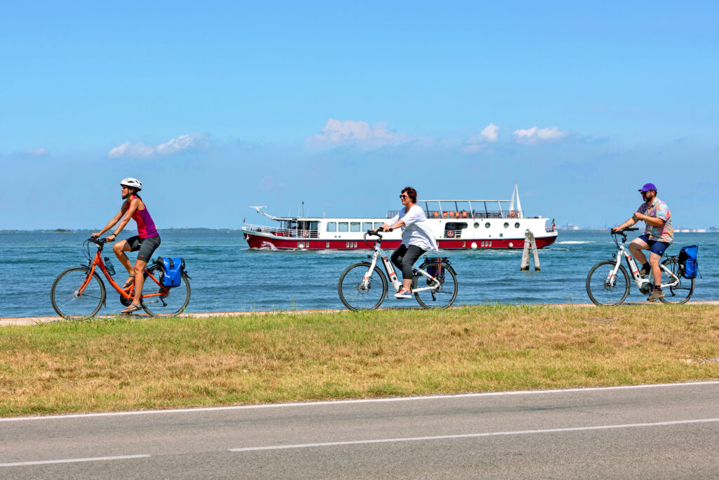 Cyclists by the sea, Italy, with Girolibero boat on the background